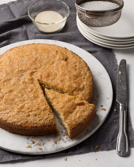 Gâteau pomme et brandy disposé sur un plateau en marbre avec une tranche découpée