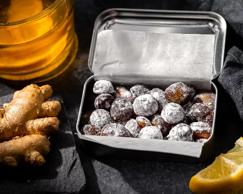 Pastilles contre la toux maison dans une boîte métallique, tranches de citron, gingembre et miel
