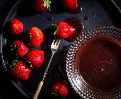 Bol en verre de sauce caramel aux fraises et au vin, avec des fraises entières